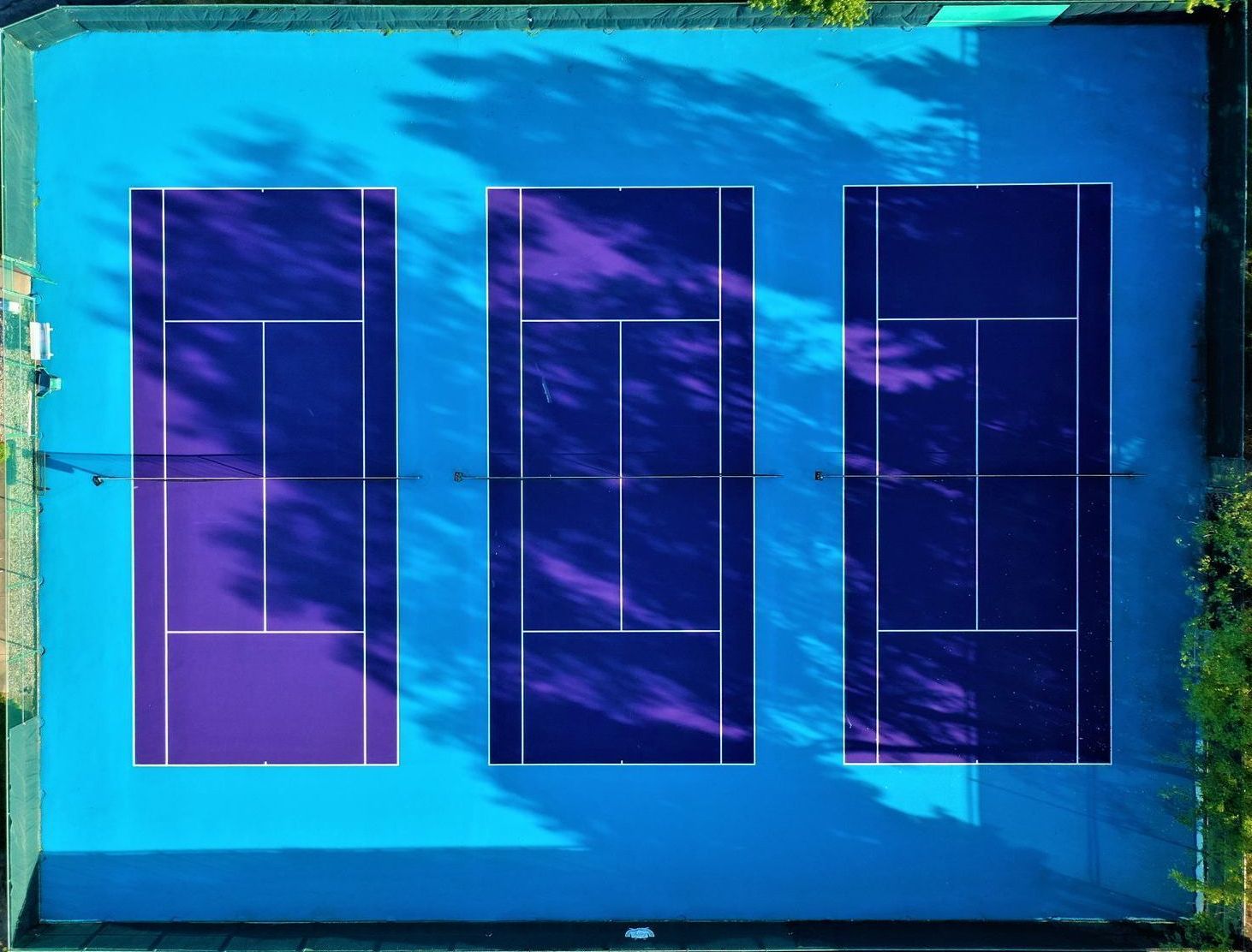 An aerial view of three tennis courts painted blue and purple