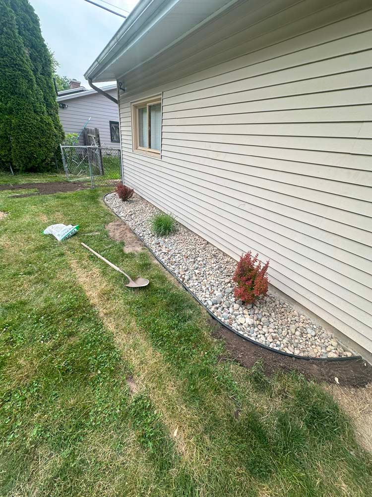 A lush green lawn is being mowed in front of a house on a sunny day.