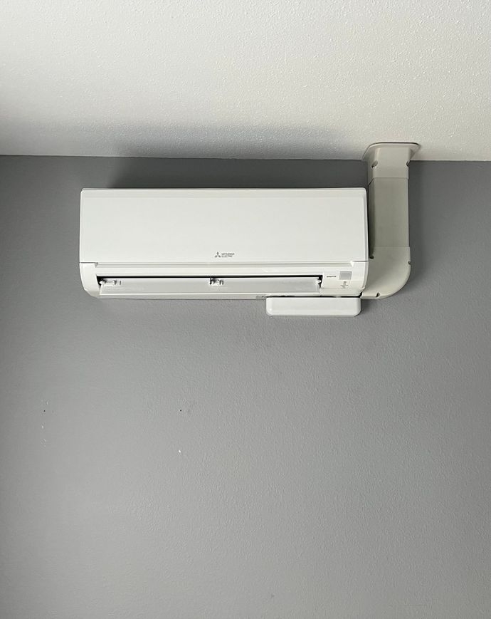 A white air conditioner is hanging from the ceiling in a room.