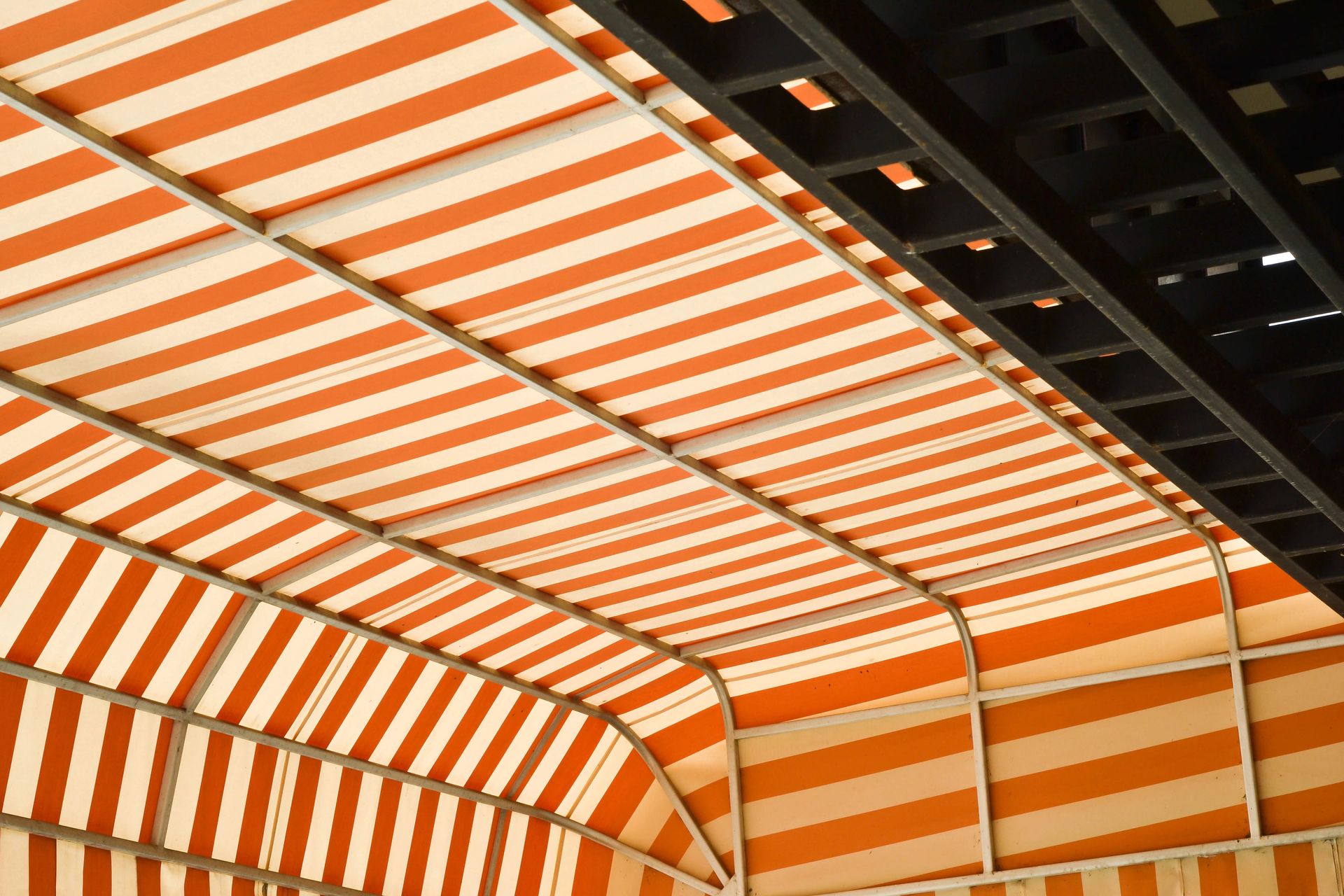 Tenda da sole a strisce arancioni e bianche con tetto curvo.