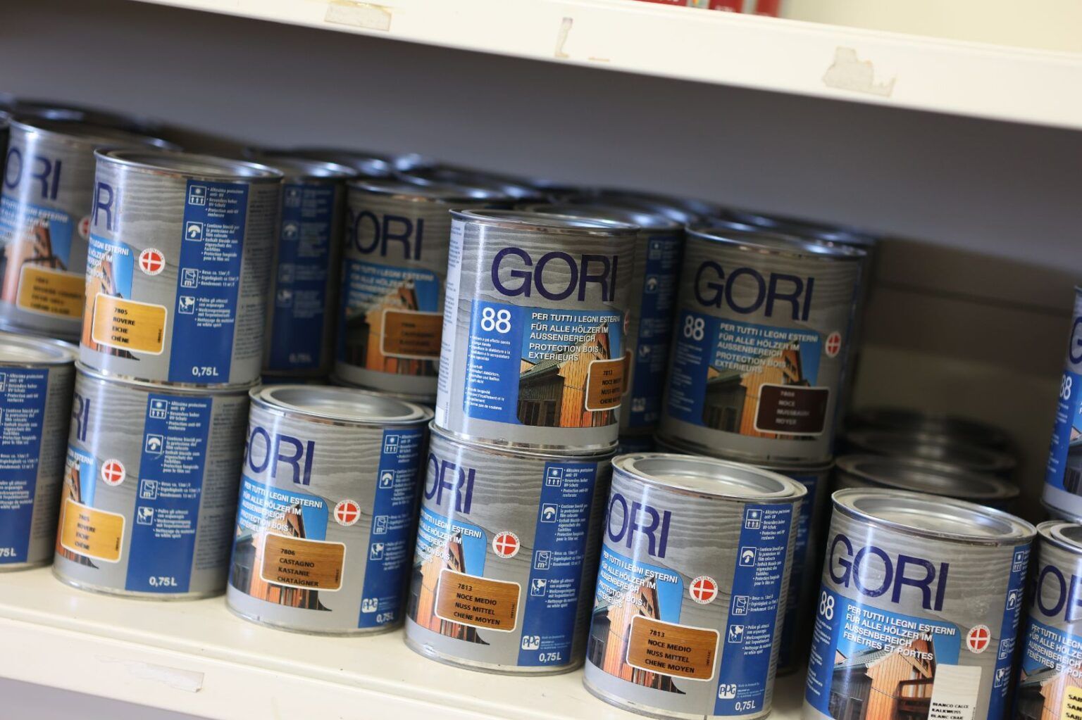 Persona che utilizza una pialla a mano su una tavola di legno, con trucioli di legno visibili.