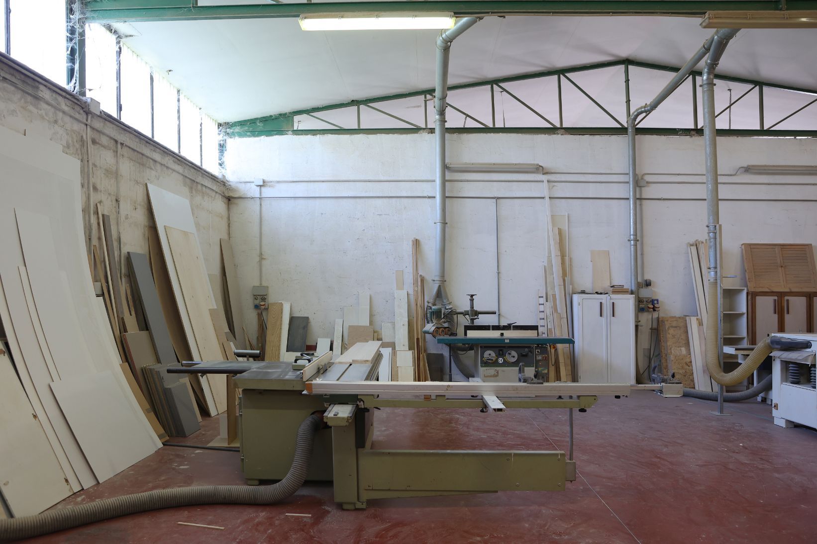 Un falegname usa una matita e un calibro per tracciare sul legno in un'officina, con segatura visibile.