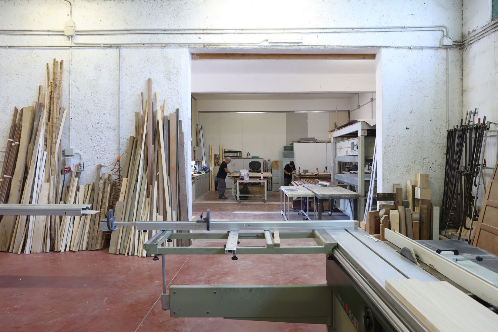 Persona che leviga una tavola di legno con un blocco abrasivo in un'officina.