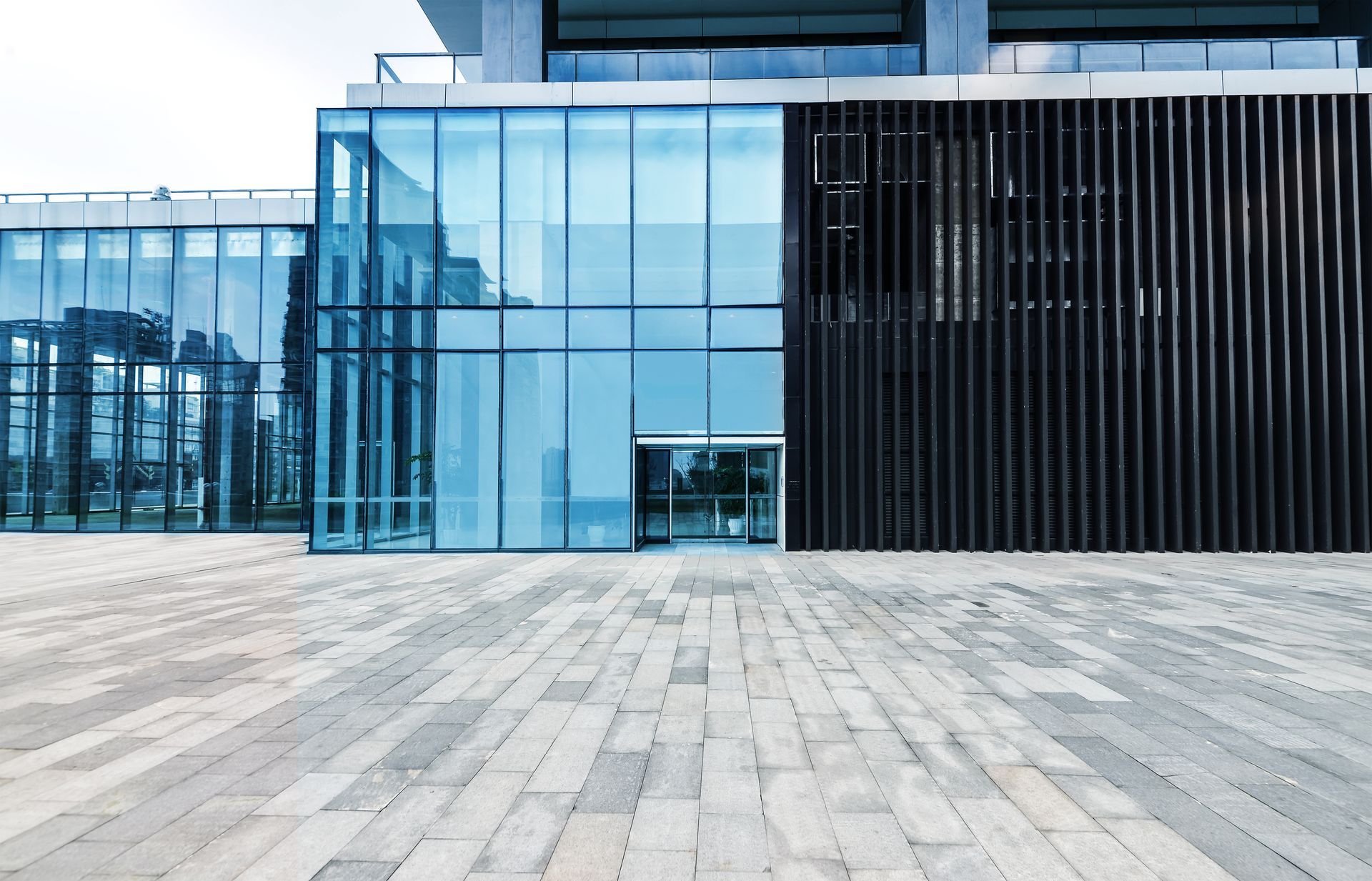 A large building with a lot of windows and a brick walkway in front of it.