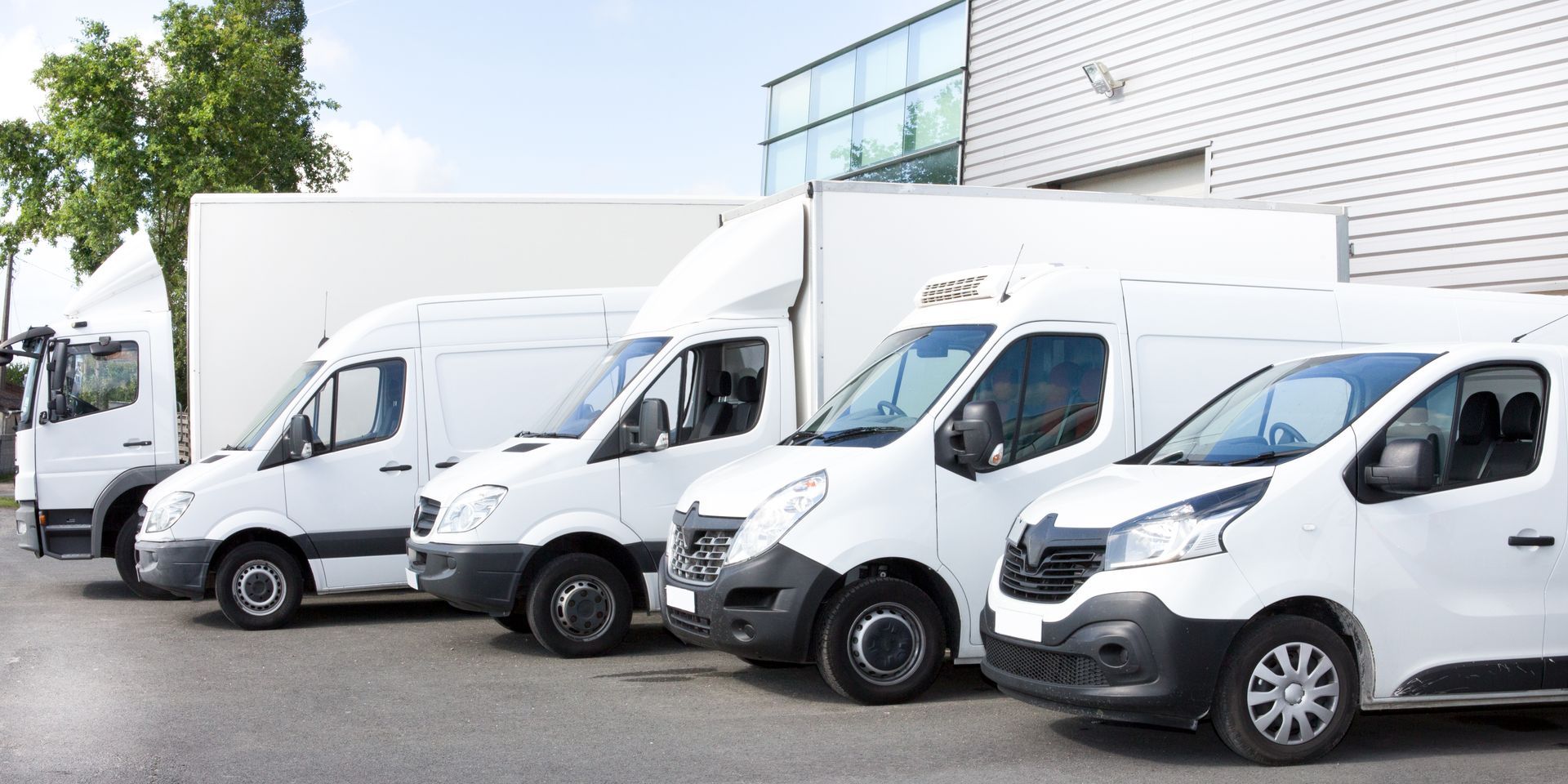 A row of white vans parked in front of a building.