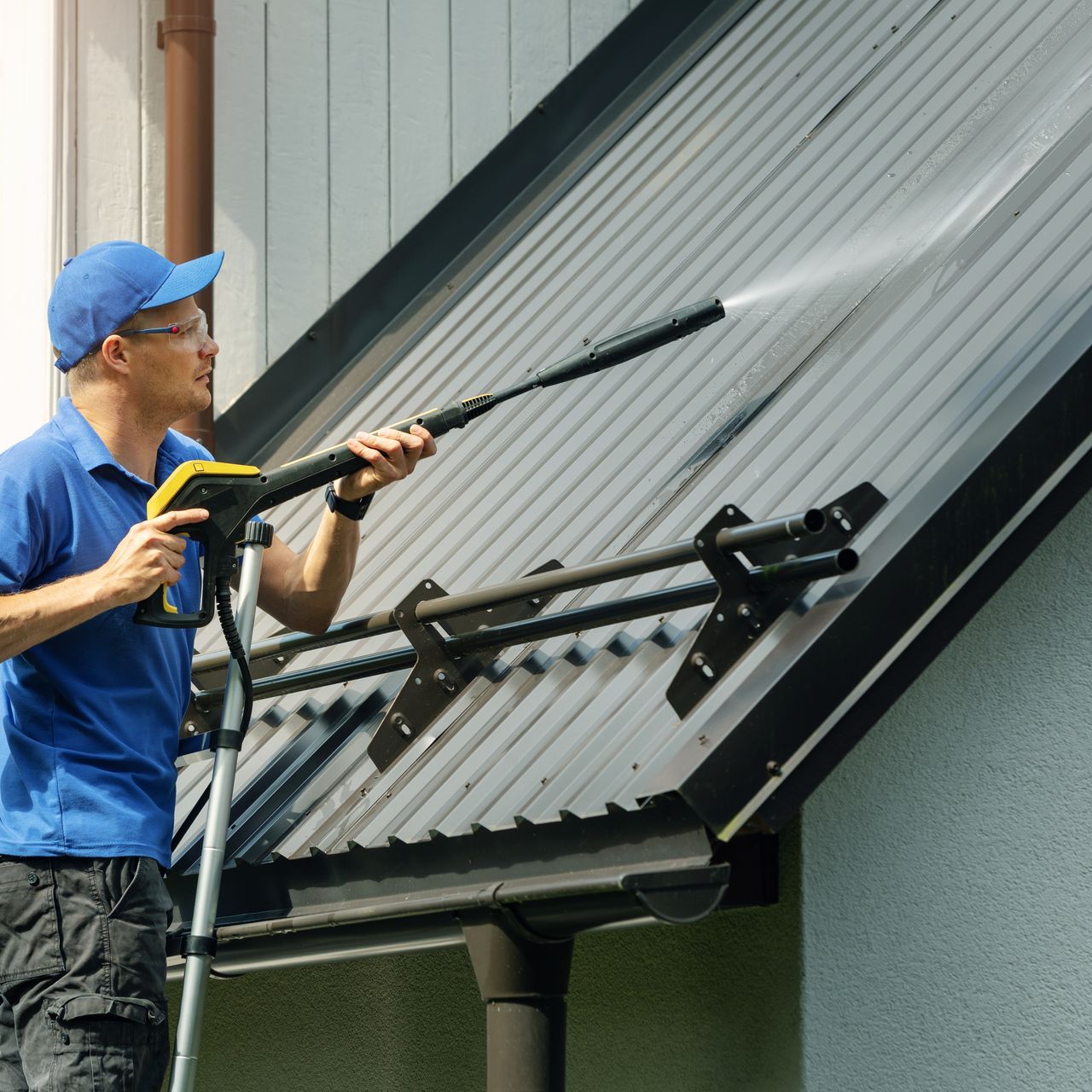 A man is using a soft pressure washer to clean a roof