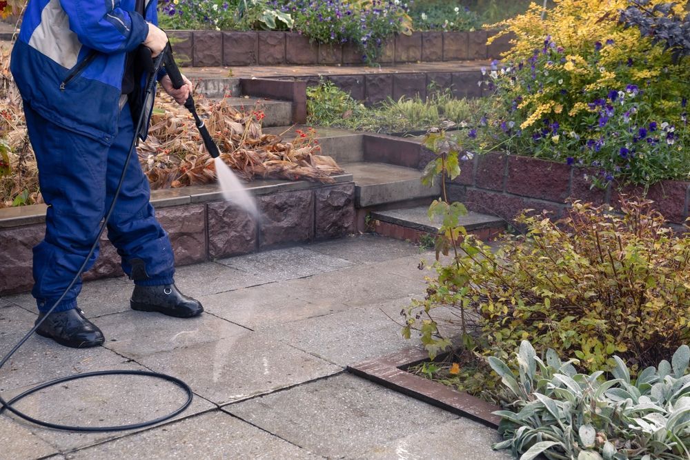 A man is cleaning a patio with a high pressure washer.