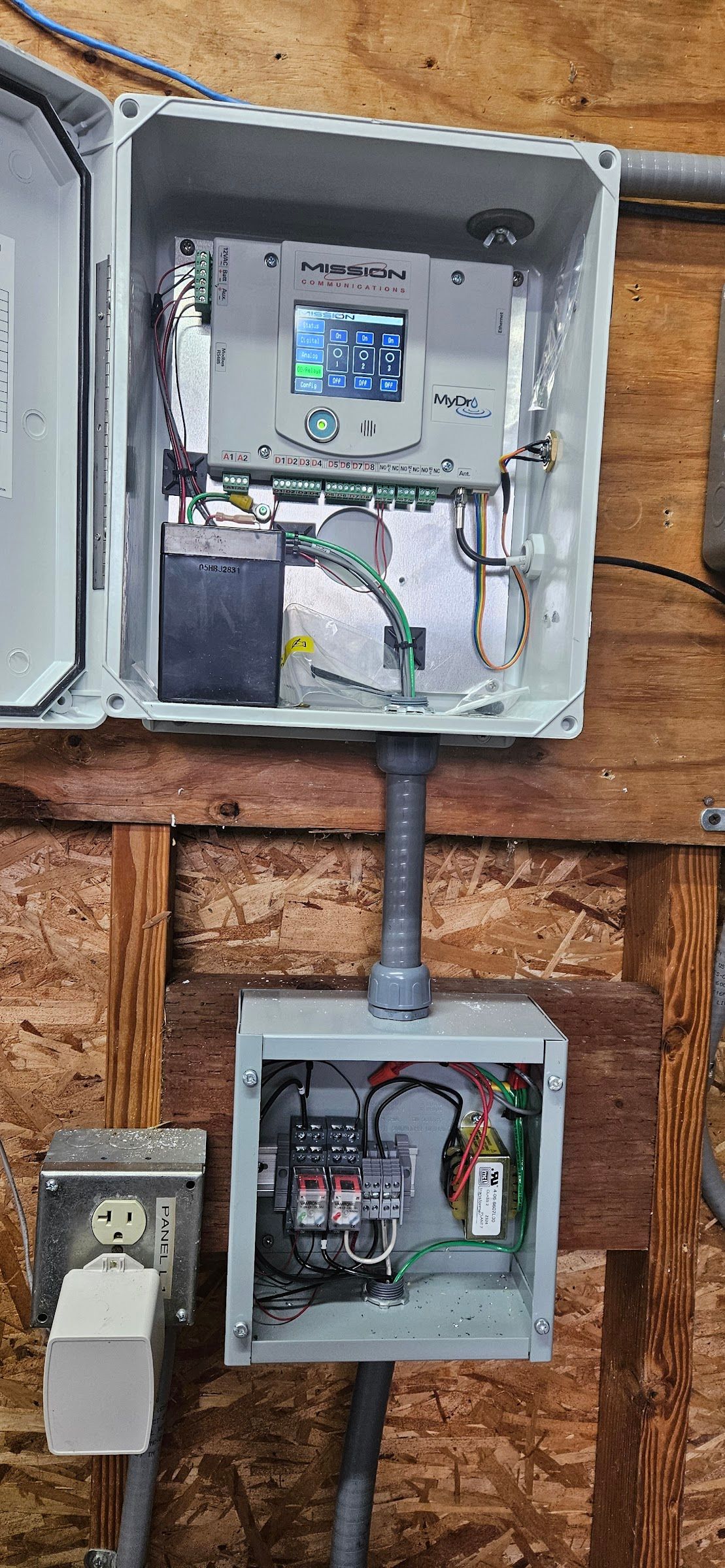 A electrical box is hanging on a wooden wall.