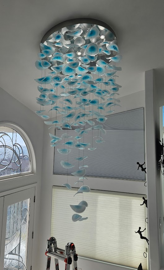 A chandelier with blue flowers hanging from the ceiling in a hallway.