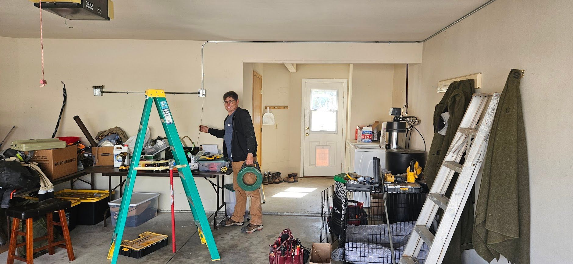 A man is standing in a garage with a ladder.