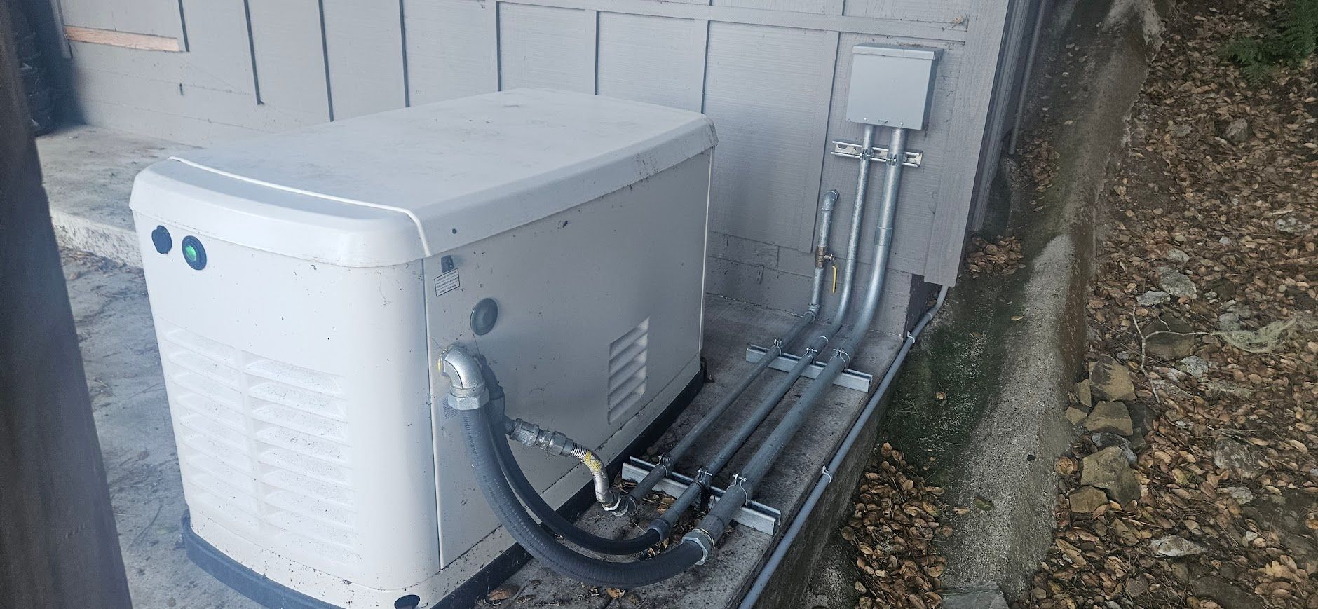 A white generator is sitting on the side of a building.