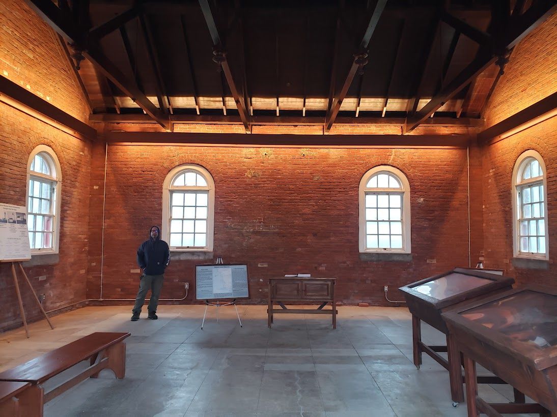 A man is standing in a room with brick walls and arched windows