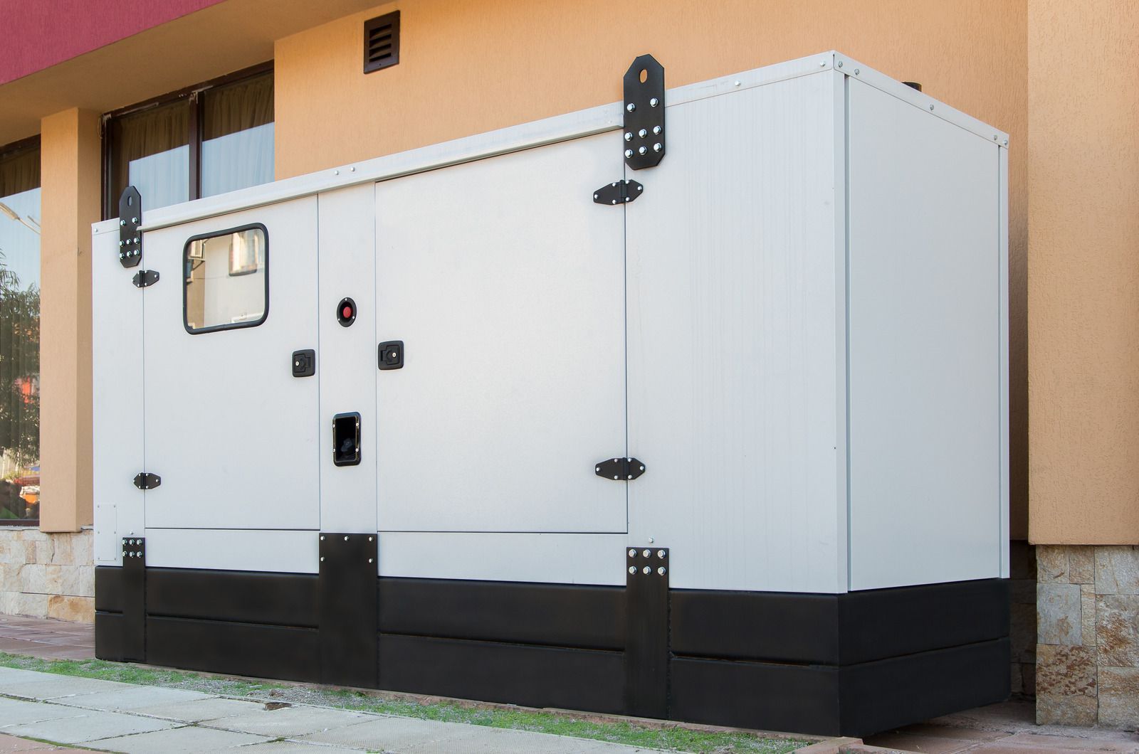 A white generator is parked in front of a building.