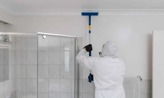 Water damage cleanup crew in action removing water stains on ceiling