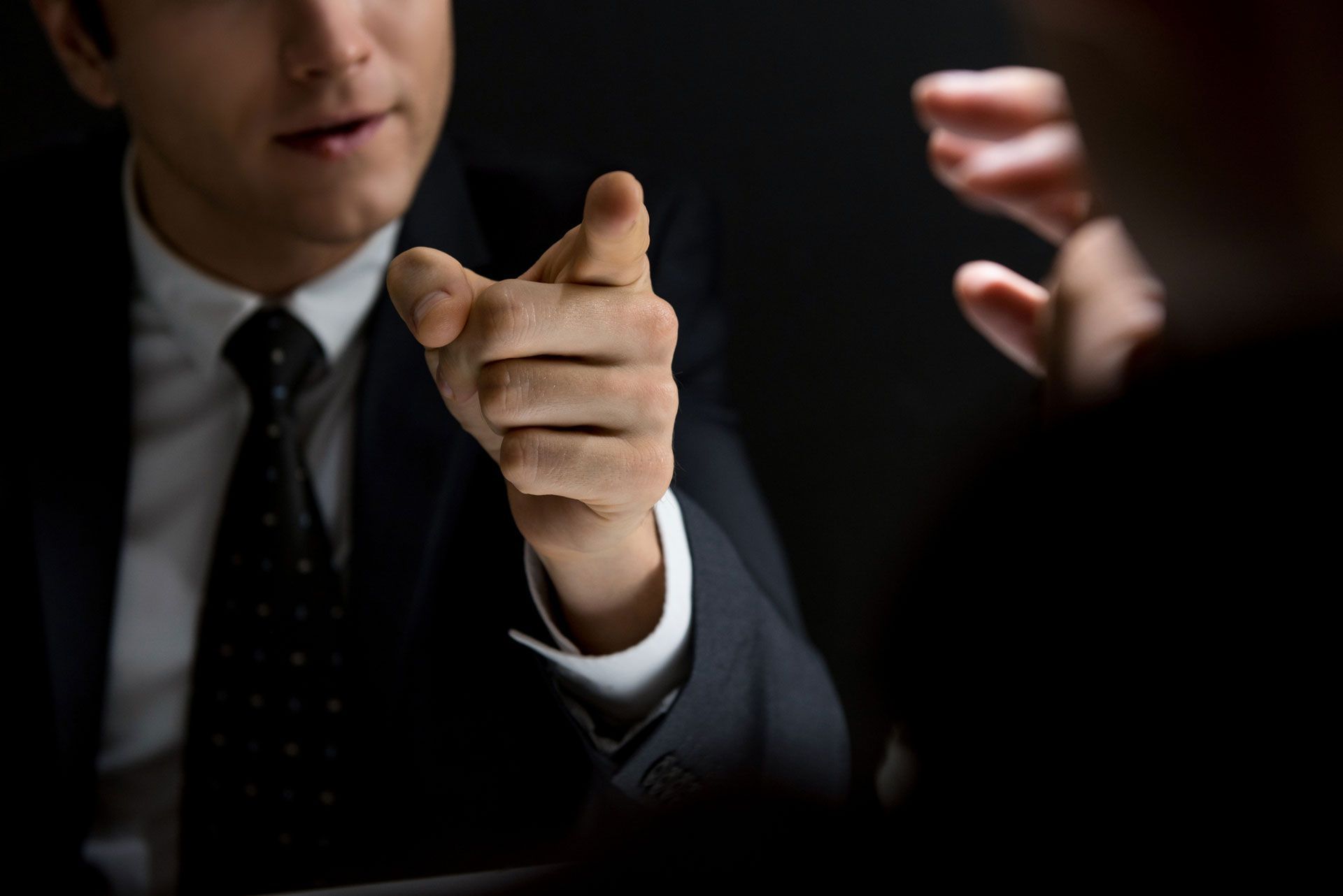 A man in a suit and tie is pointing at another man.