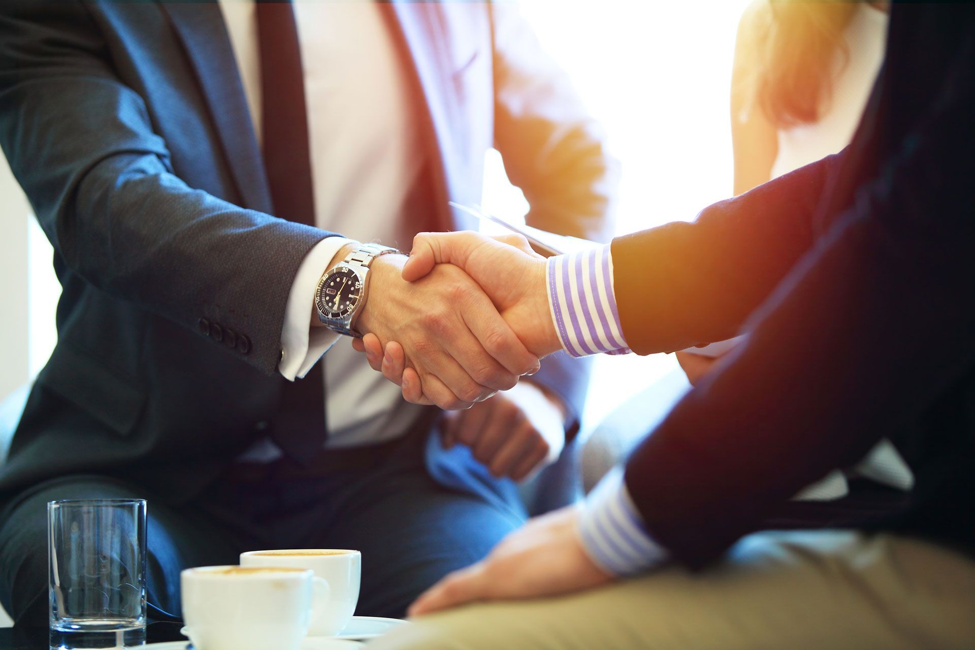 A group of business people are shaking hands while sitting at a table.