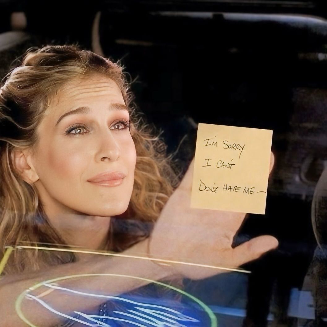 woman holding up a post it saying sorry don't hate me