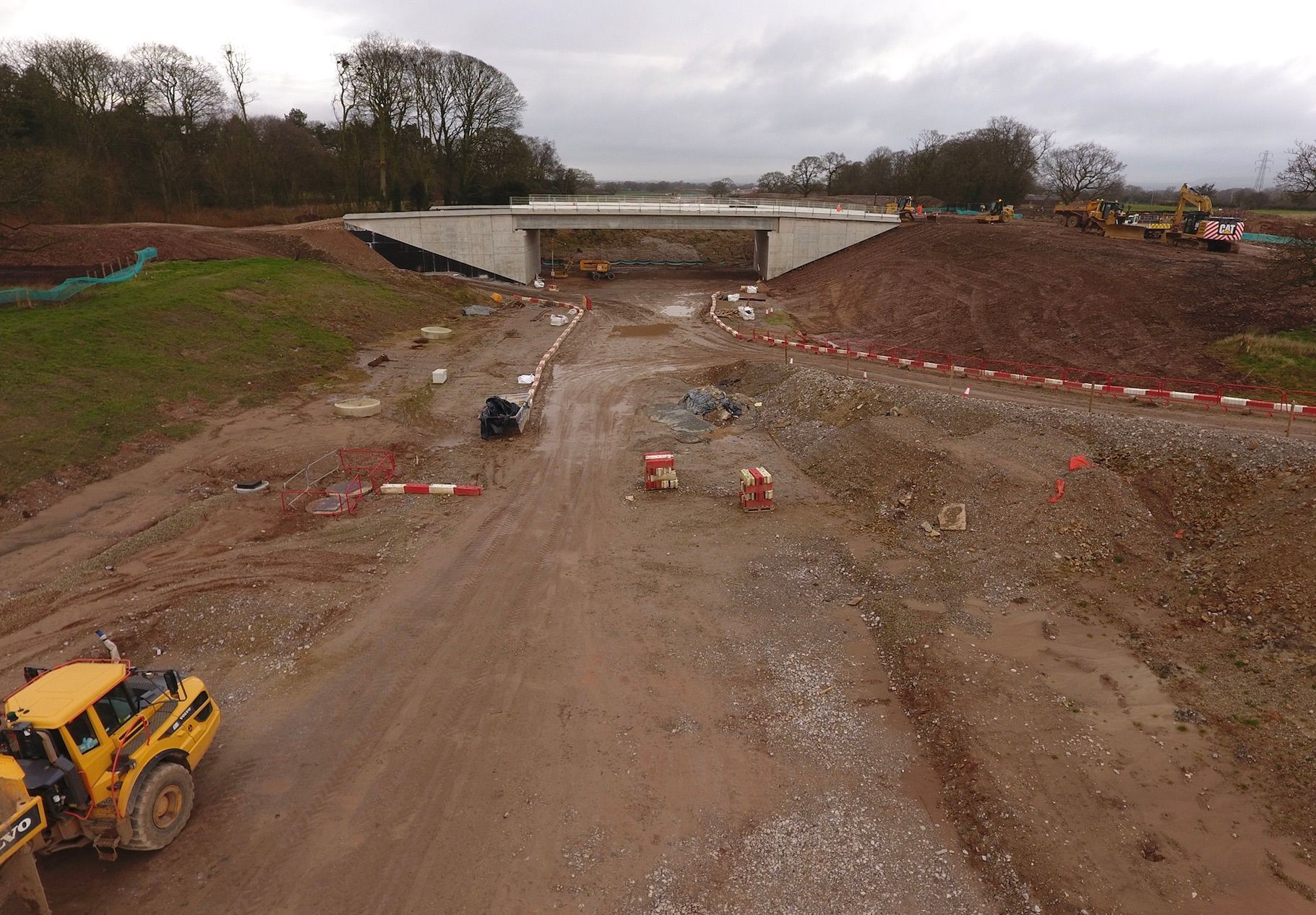 An aerial view of a construction site with a bridge in the background.