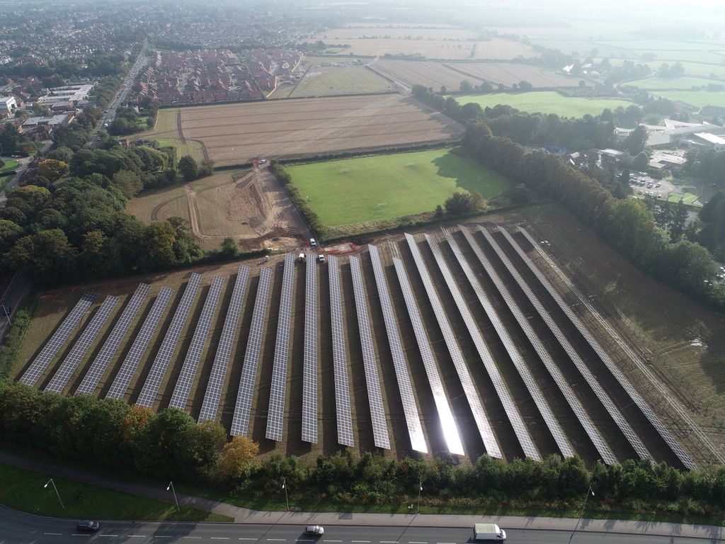 An aerial view of rows of solar panels in a field