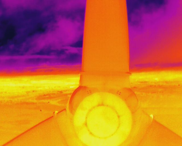A thermal image of a lighthouse with a purple sky in the background.