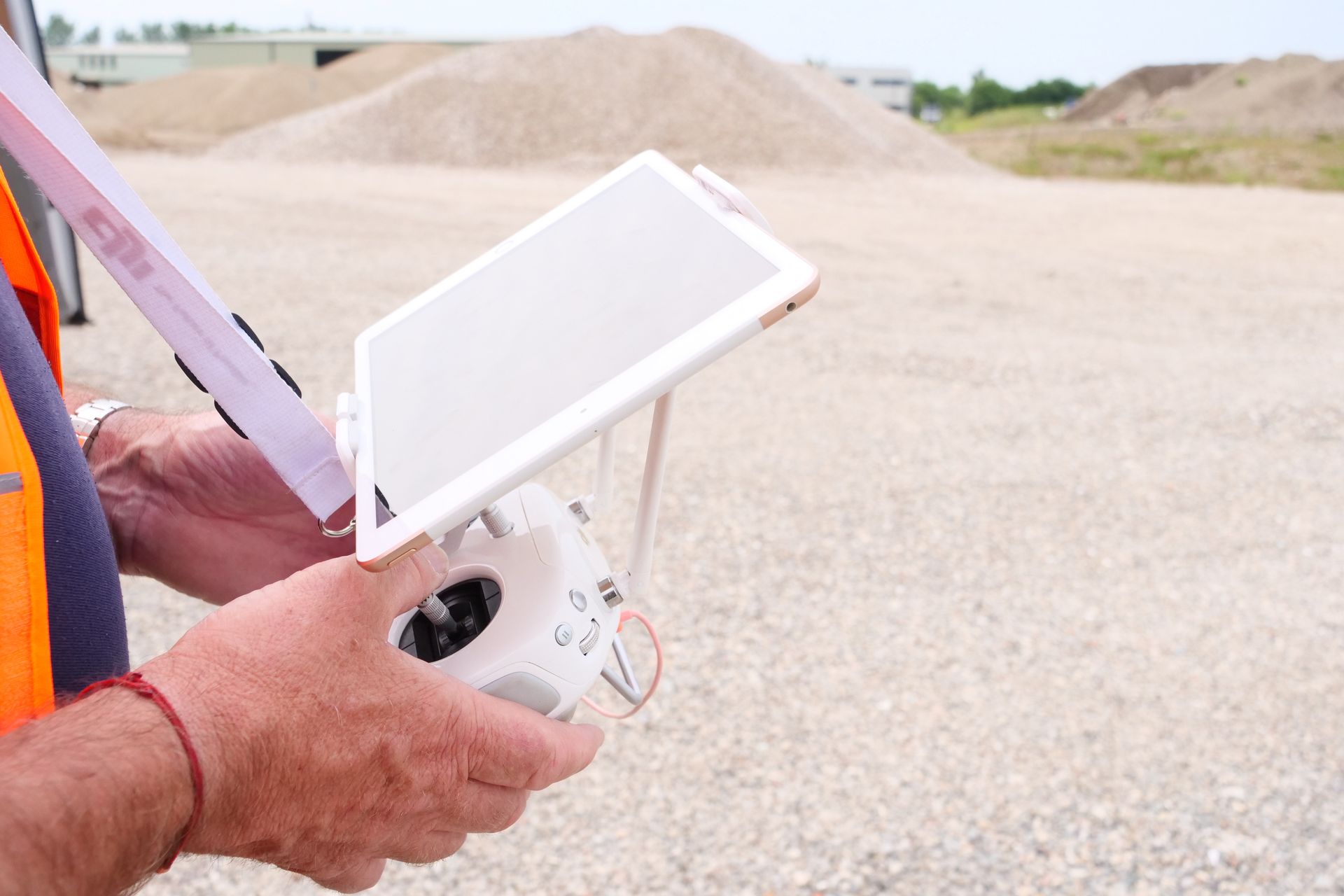 A man is holding a tablet and a remote control in his hands.