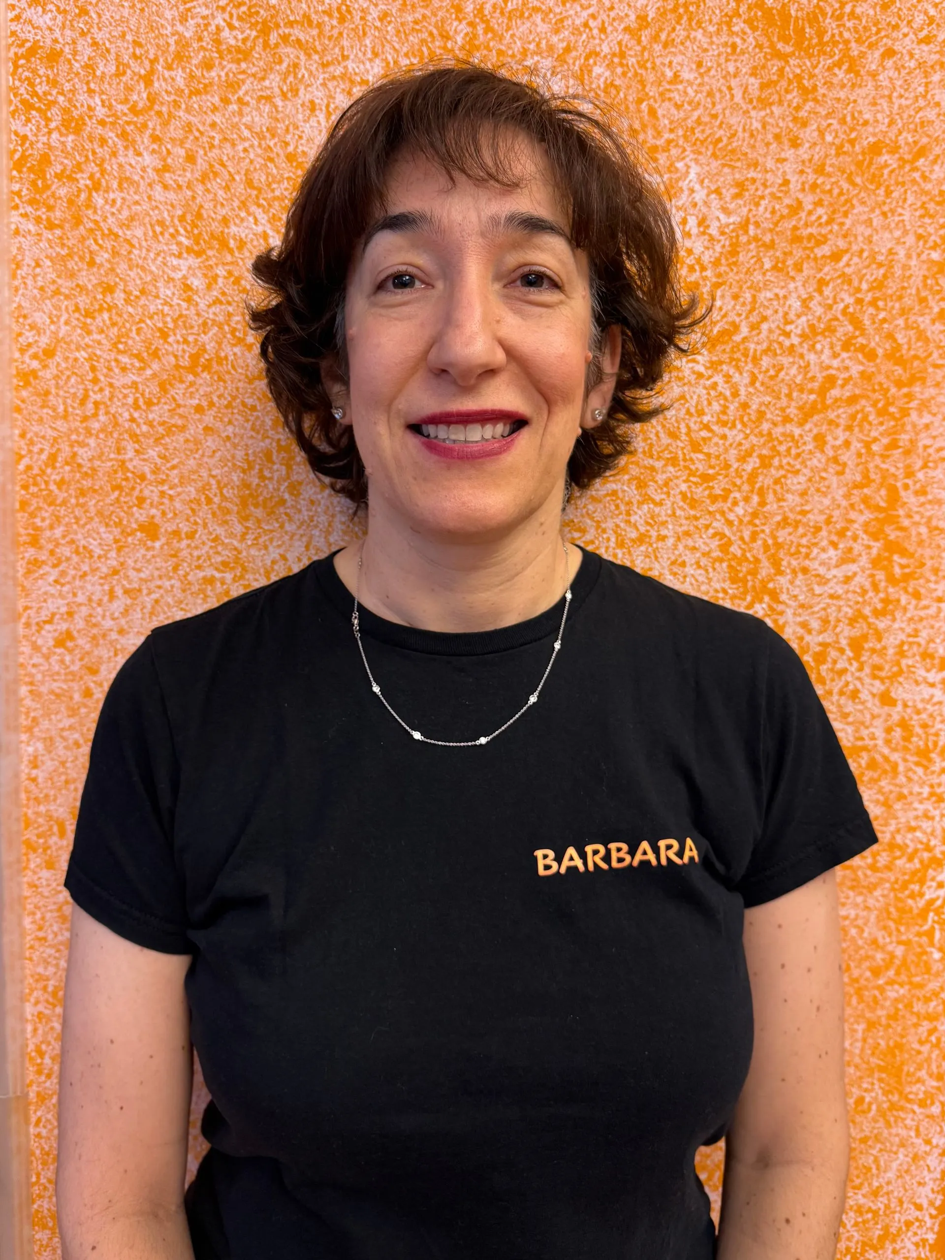 Donna con capelli castani corti che indossa una maglietta nera con la scritta