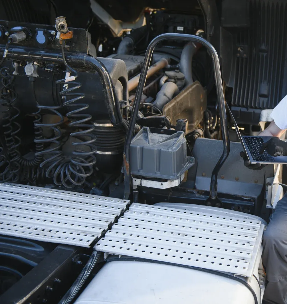 Semi-truck engine being inspected with a laptop.