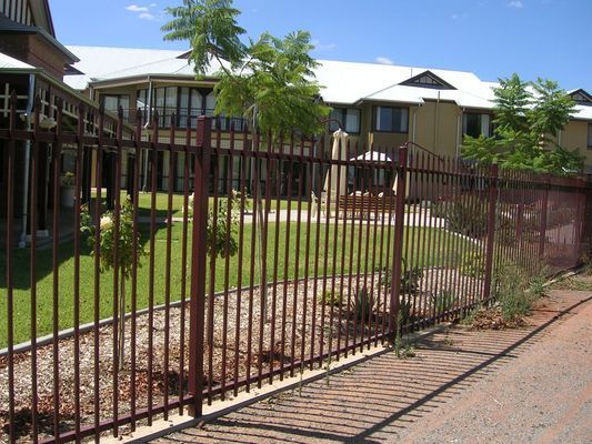 A large house is behind a metal fence