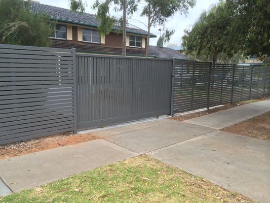 A fence with a sliding gate in front of a house.