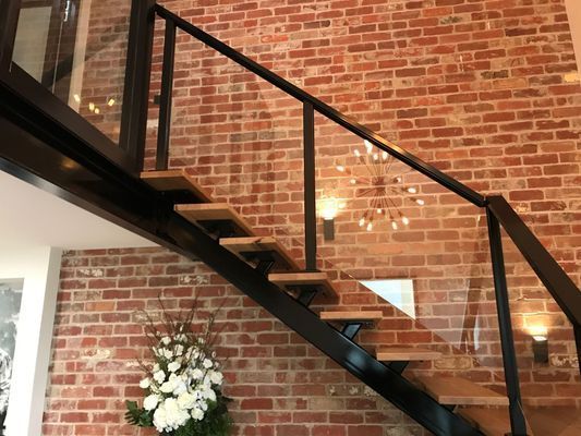 A staircase with a brick wall and a glass railing