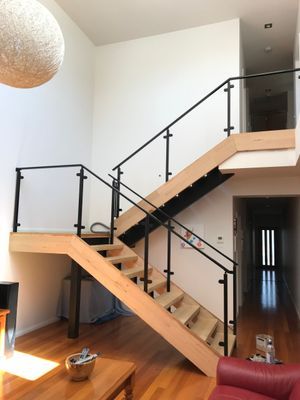 A wooden staircase with a black railing in a living room