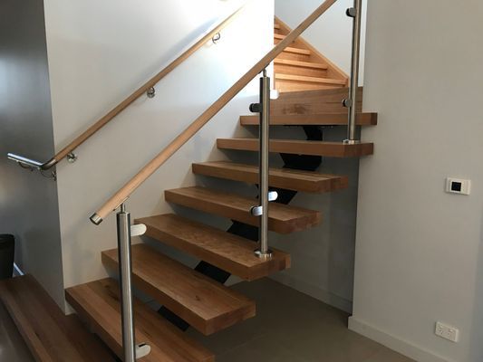 A wooden staircase with a stainless steel railing