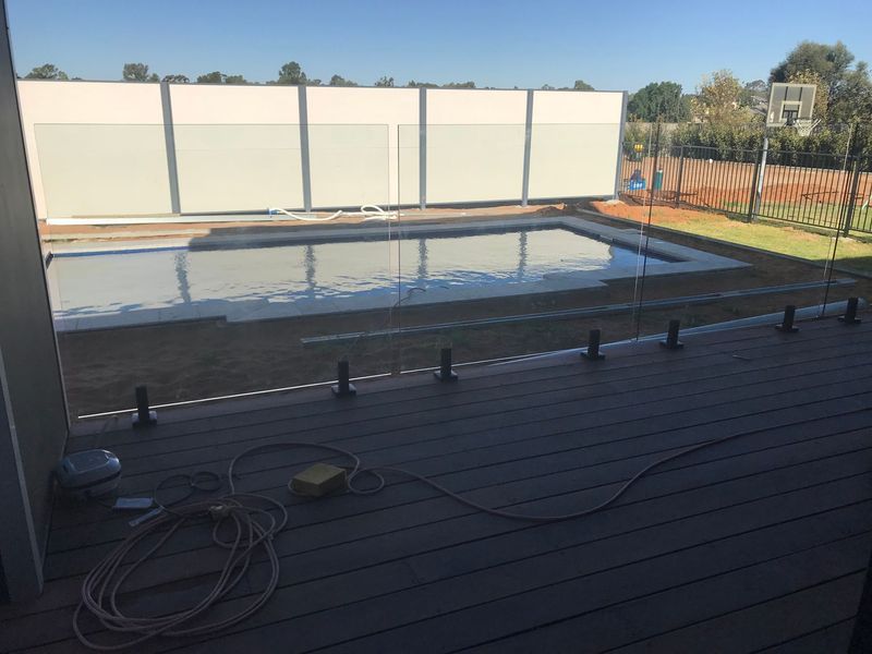 A swimming pool with a glass fence around it