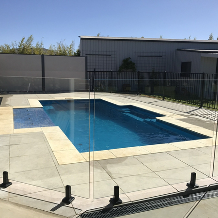 A large swimming pool with a glass fence around it