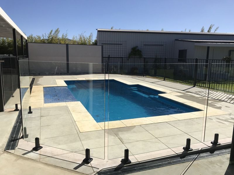 A large swimming pool with a glass fence around it.