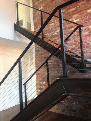 A staircase with a black railing and a brick wall in the background.