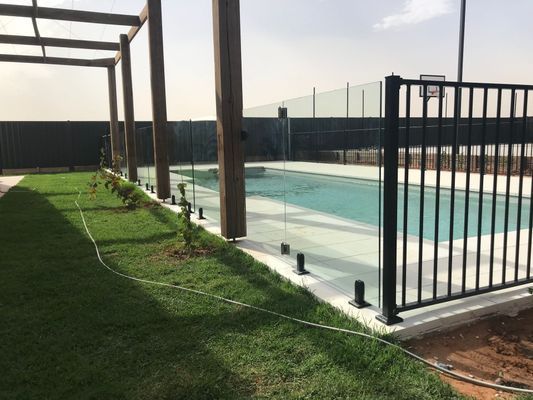 A fence surrounds a swimming pool in a backyard.