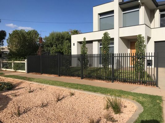 A large white house with a black fence in front of it.