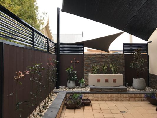 A patio with a black umbrella and a fence