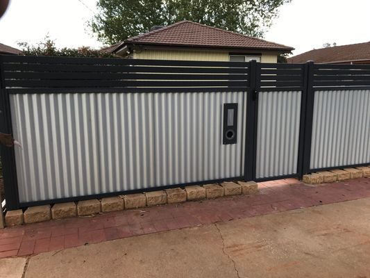 A metal fence with a gate in front of a house.