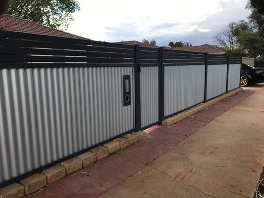 A white and black fence with a gate in the middle of it.