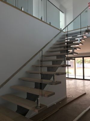 A wooden staircase with a glass railing in a house.