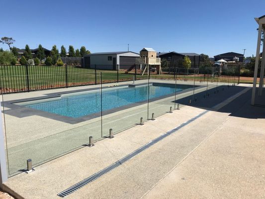 A large swimming pool with a glass fence around it