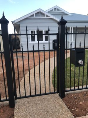 A black fence with a mailbox in front of a house.