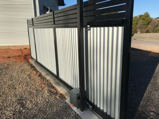 A sliding gate with a black frame and a white fence