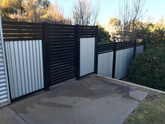 A black and white fence is sitting on top of a concrete driveway.