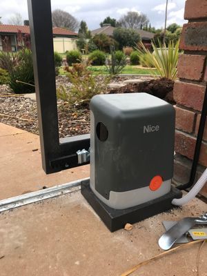 A nice sliding gate motor is sitting next to a brick wall.