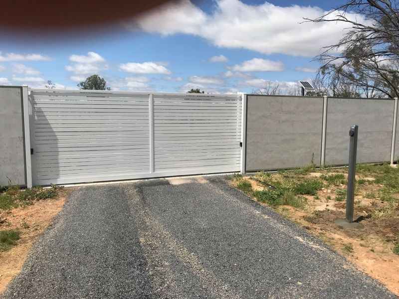 A white gate is sitting on the side of a road.