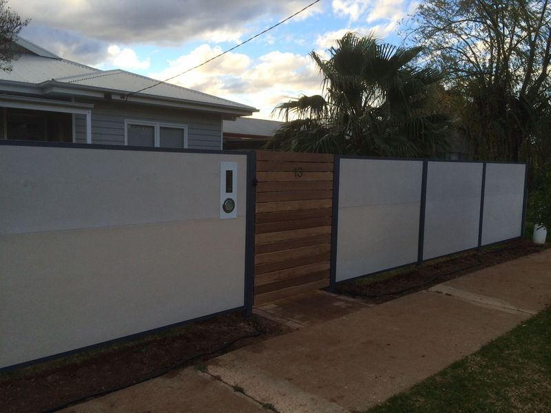 A white fence with a wooden gate in front of a house