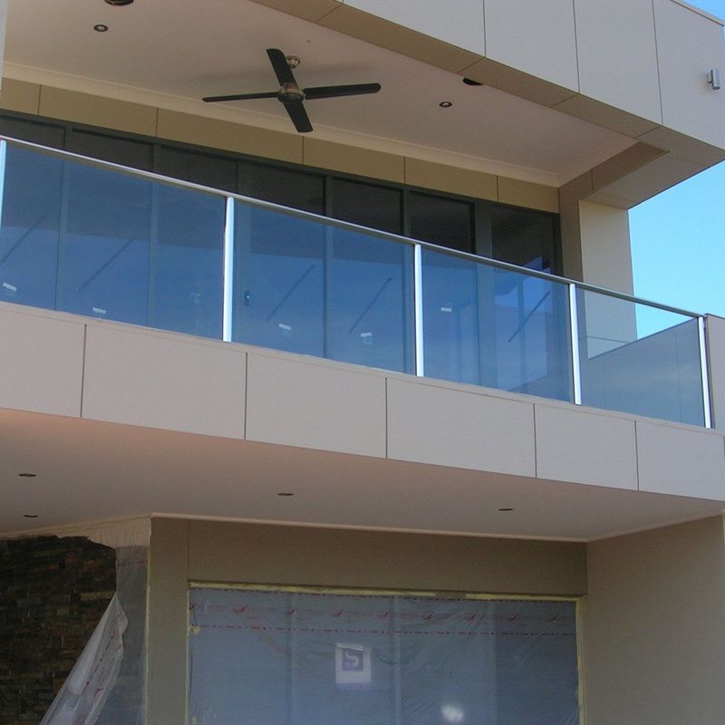 A balcony with a glass railing and a ceiling fan
